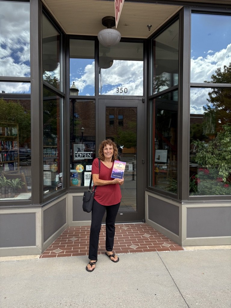 Leslie holding Peaks & Valleys at the front door of Grand Valley Books